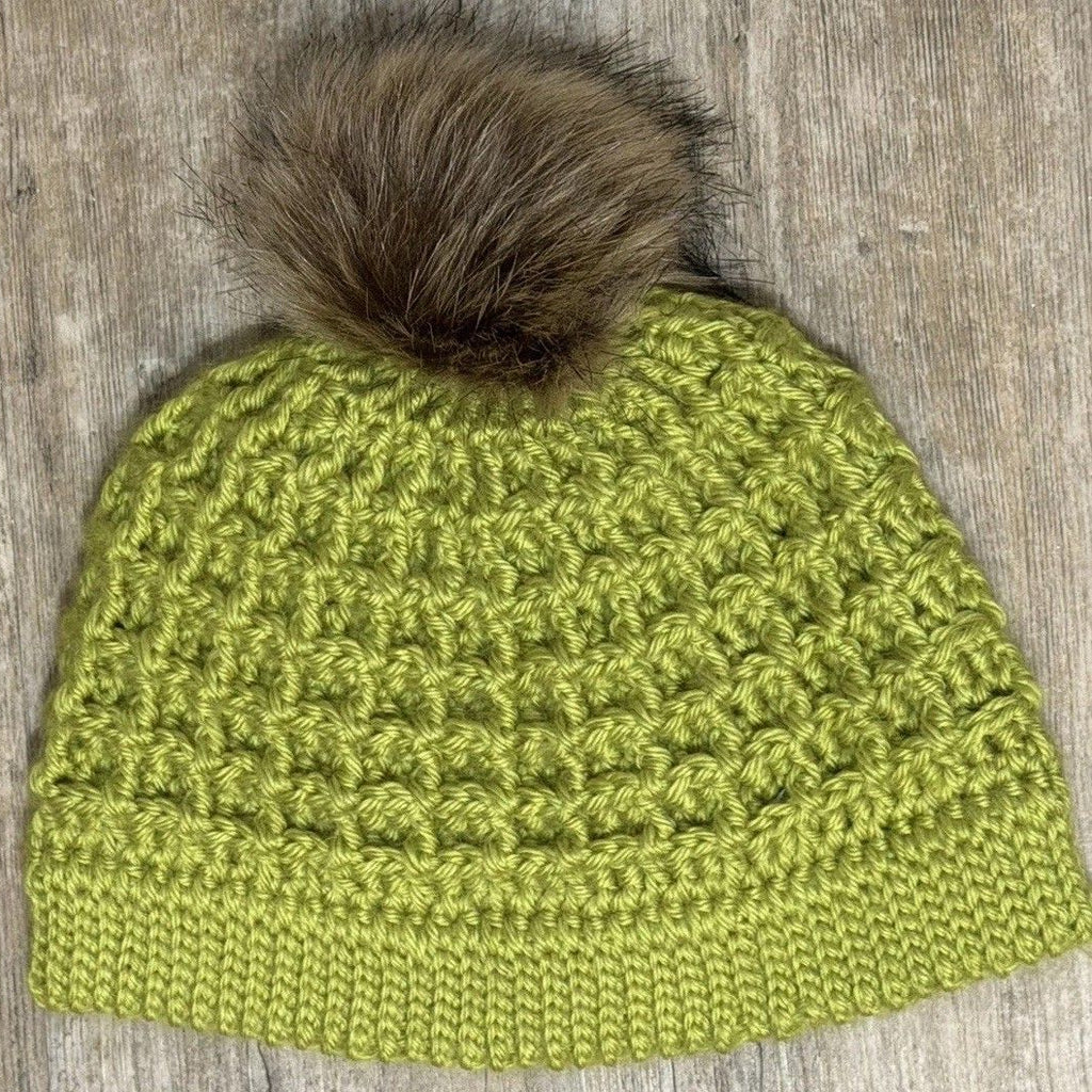 Hand-crocheted green textured hat with a brown faux-fur pom-pom