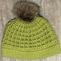 Hand-crocheted green textured hat with a brown faux-fur pom-pom