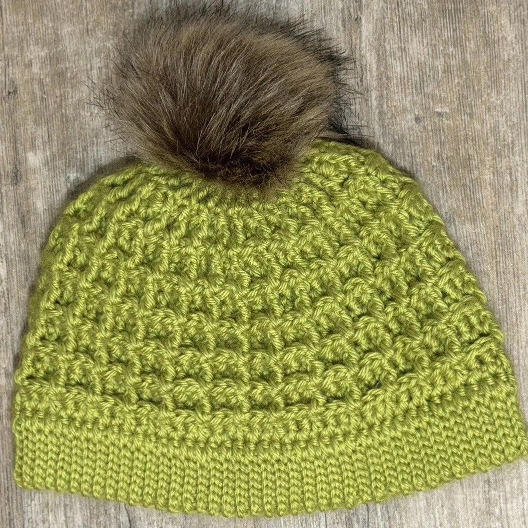 Hand-crocheted green textured hat with a brown faux-fur pom-pom