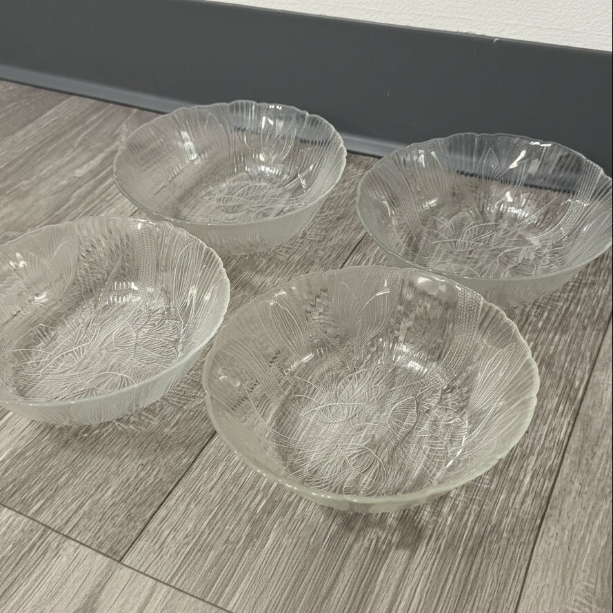 Four clear glass bowls with textured design on a wooden surface