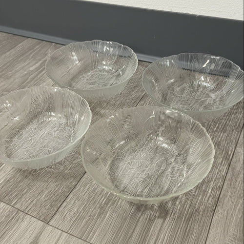 Four clear glass bowls with textured design on a wooden surface