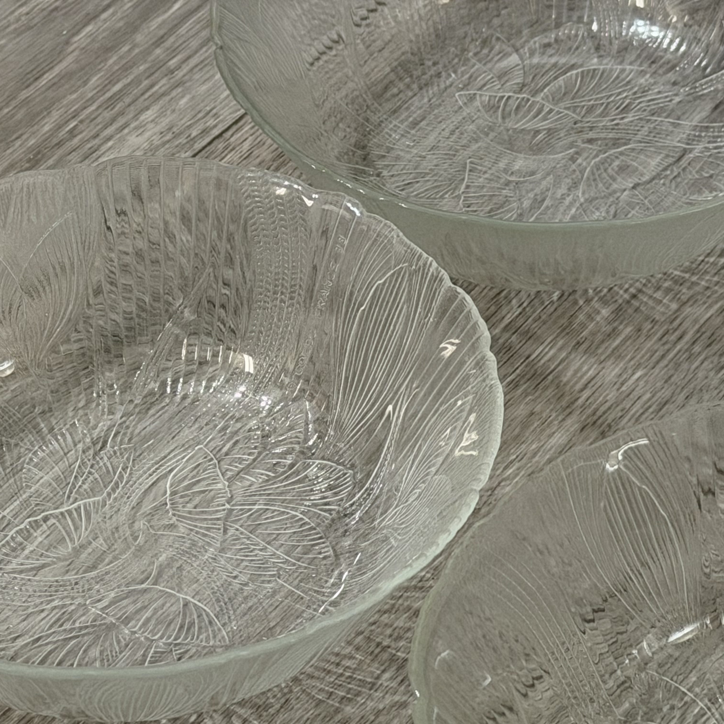 Set of glass bowls with leaf patterns on a wooden surface